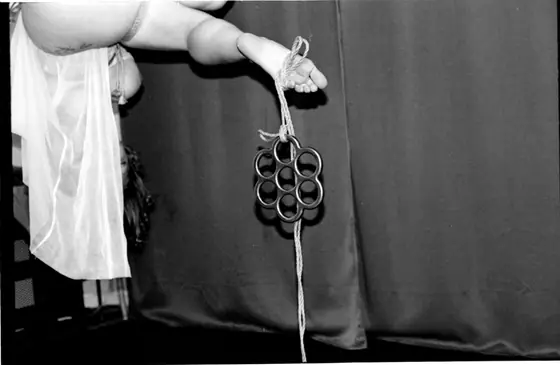 Person suspending themselves with one foot tied to a looped rope, holding a cluster of round metal rings with the same foot.